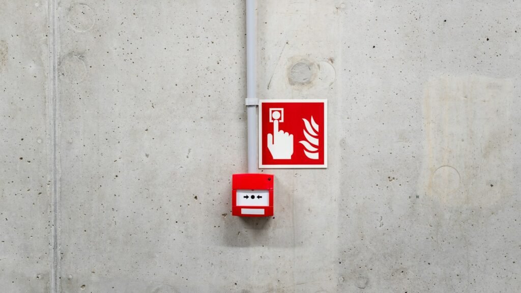 نقطة نداء يدوية لFire Alarm مع لافتة إرشادية على جدار خرساني | Manual fire alarm call point and sign on a concrete wall